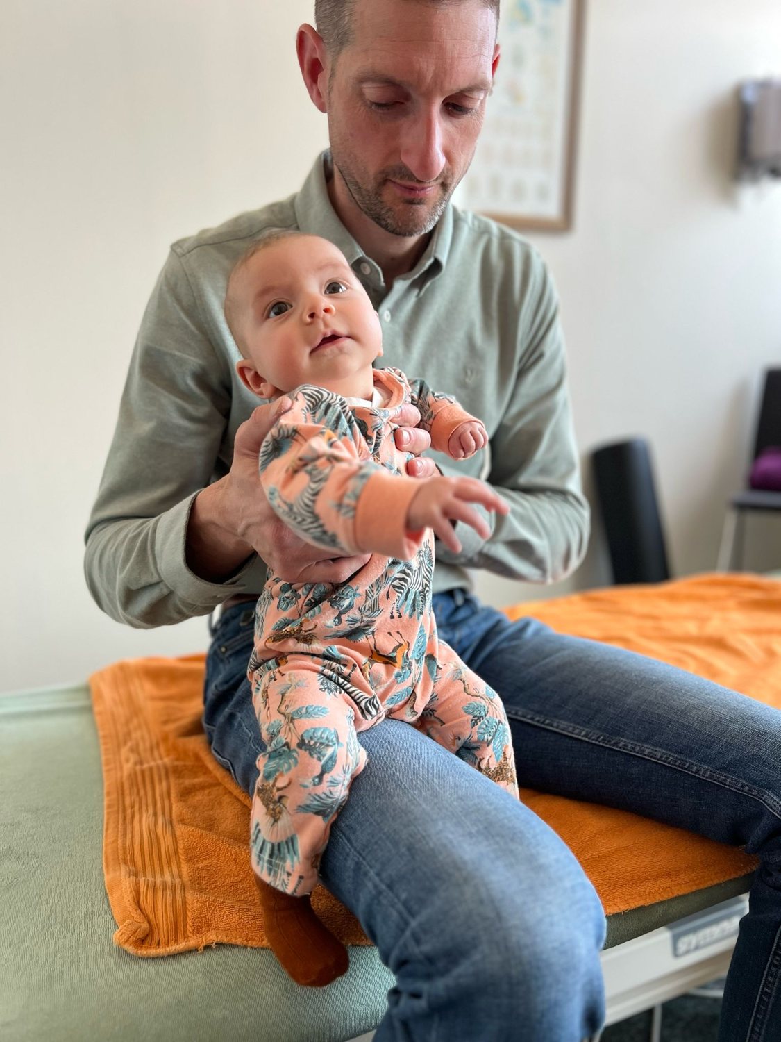 Wouter houdt een baby ondersteund op schoot